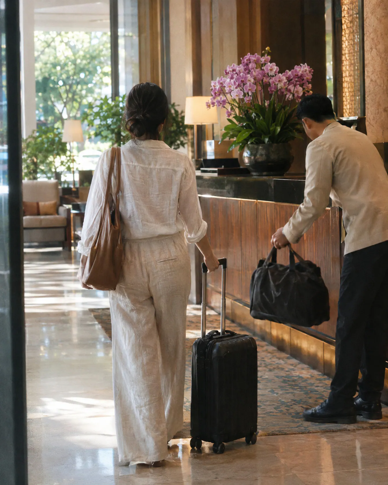 A woman arriving at a boutique hotel lobby in Bangkok as a porter takes her bag